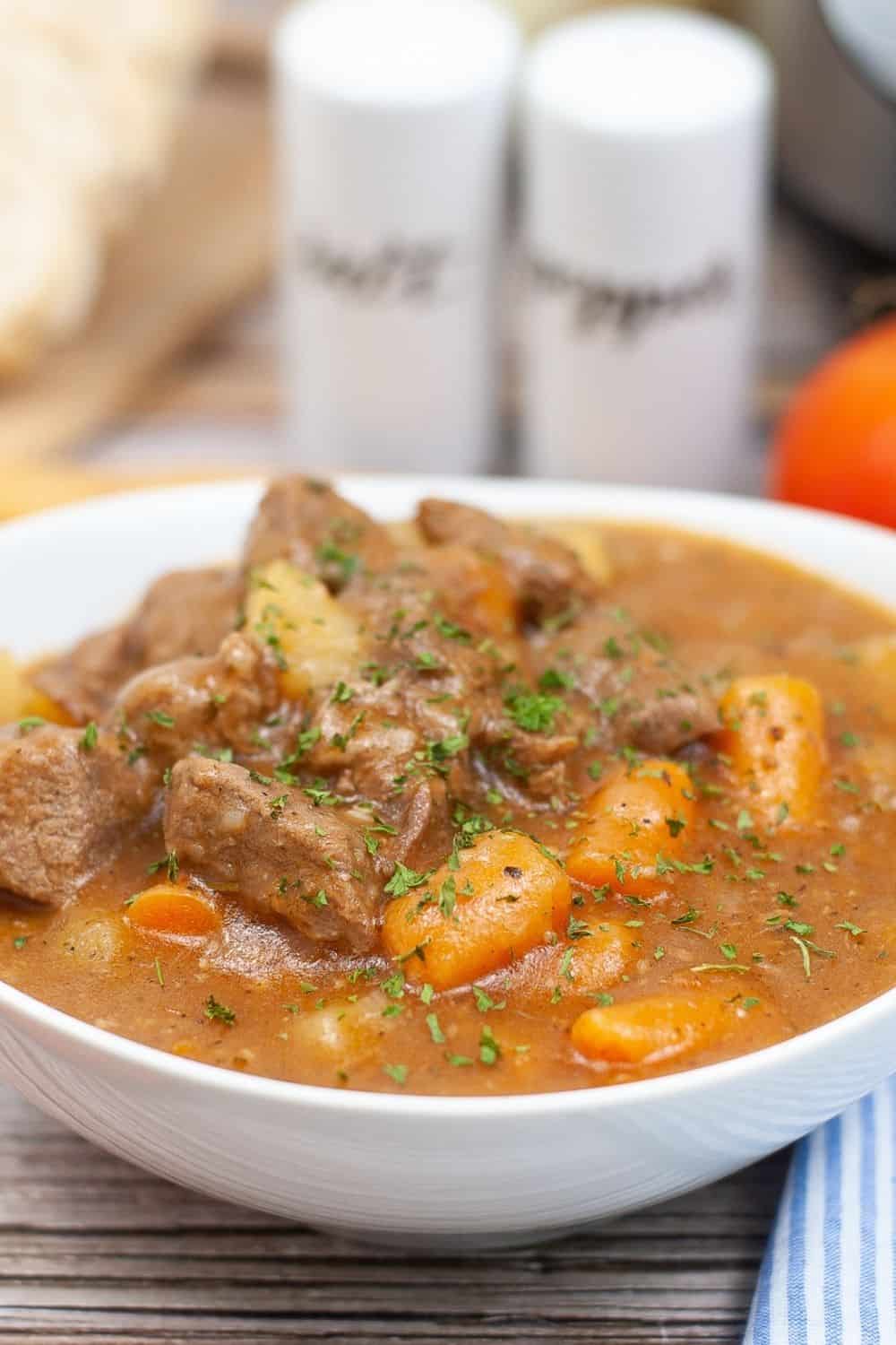 white bowl containing pressure cooker beef stew, with salt and pepper shakers in the background