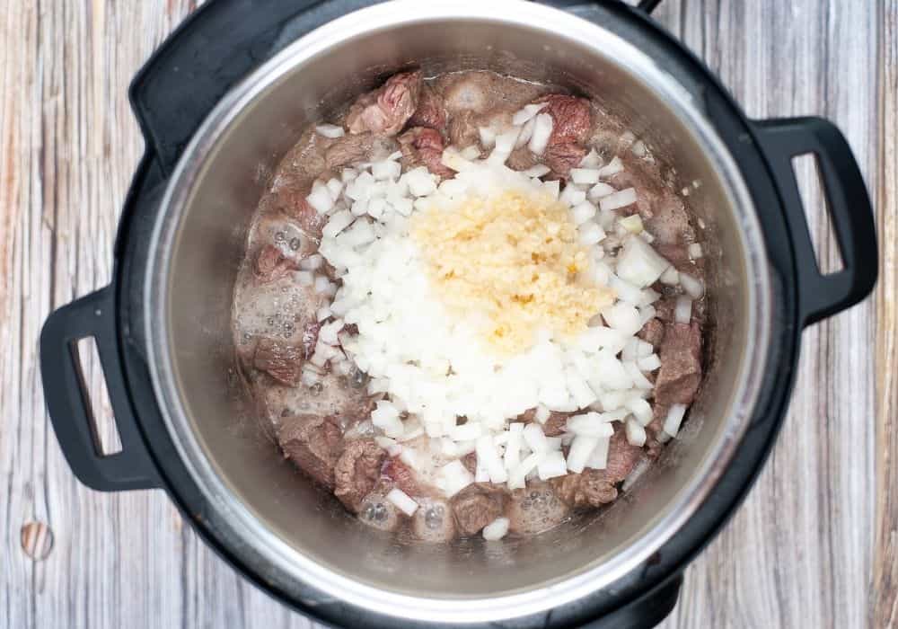 browned beef in the pressure cooker, along with onions and garlic