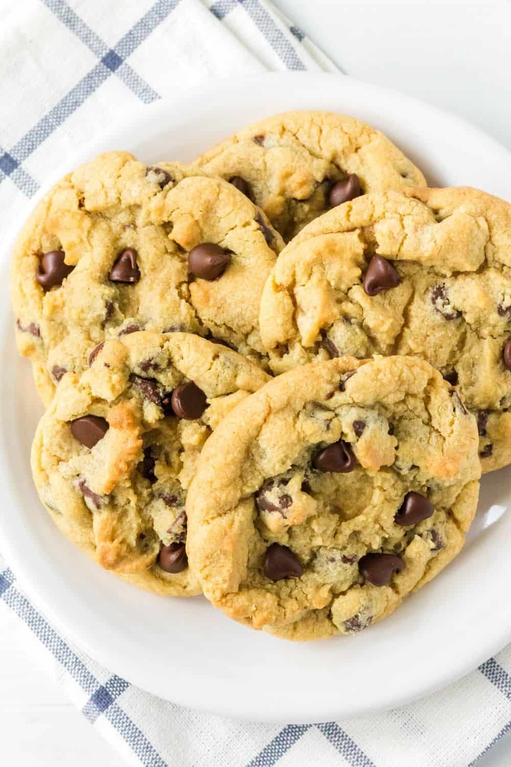 several soft and chewy chocolate chip cookies not containing brown sugar rest on a white plate for serving