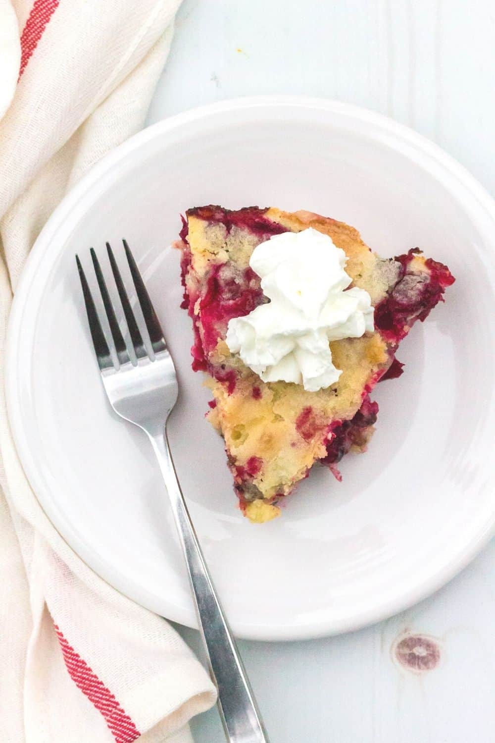 overhead view of a slice of nantucket cranberry dessert on a white plate with a fork