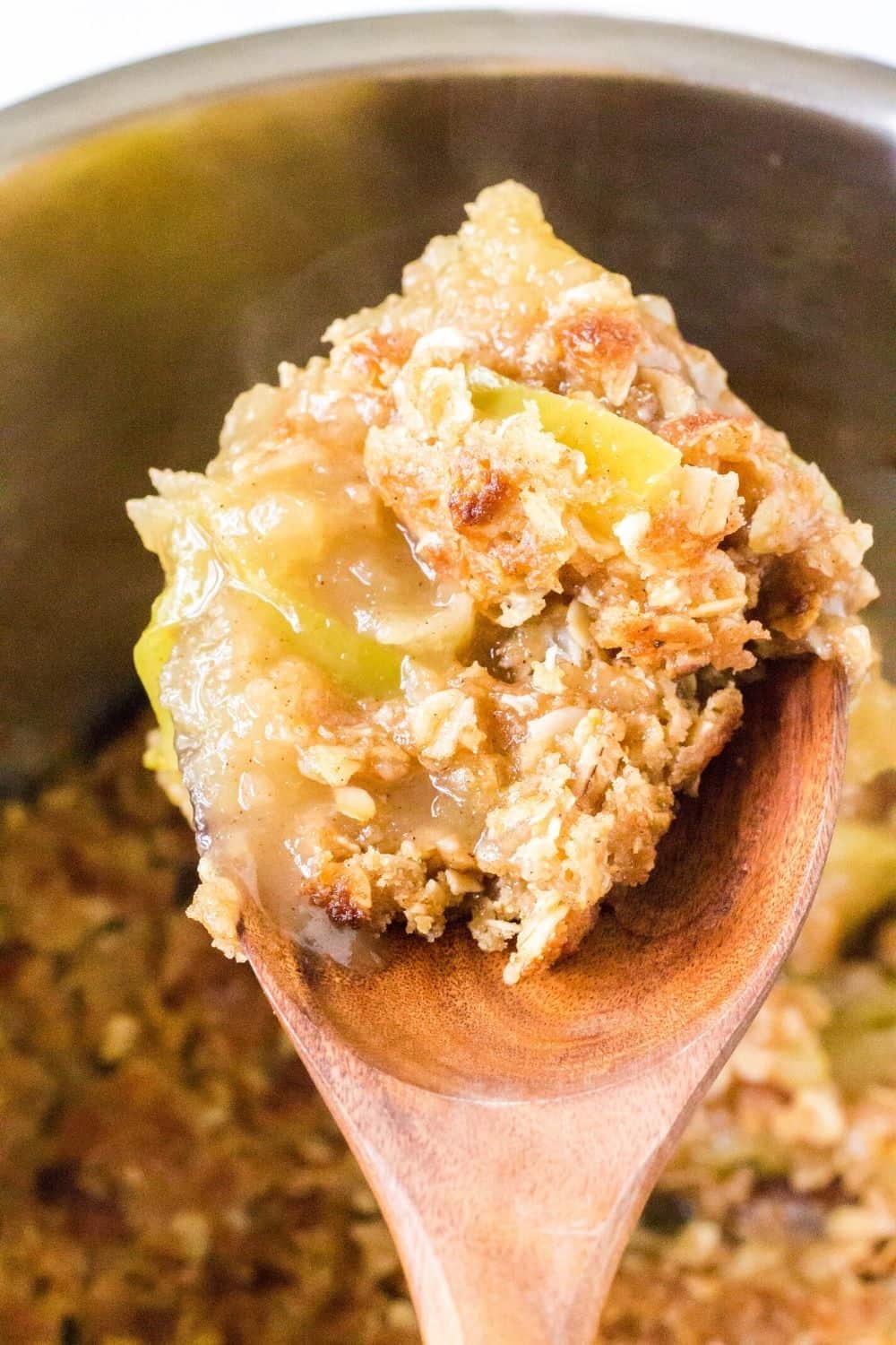 Wooden spoon scooping out some apple crisp cooked in the Instant Pot