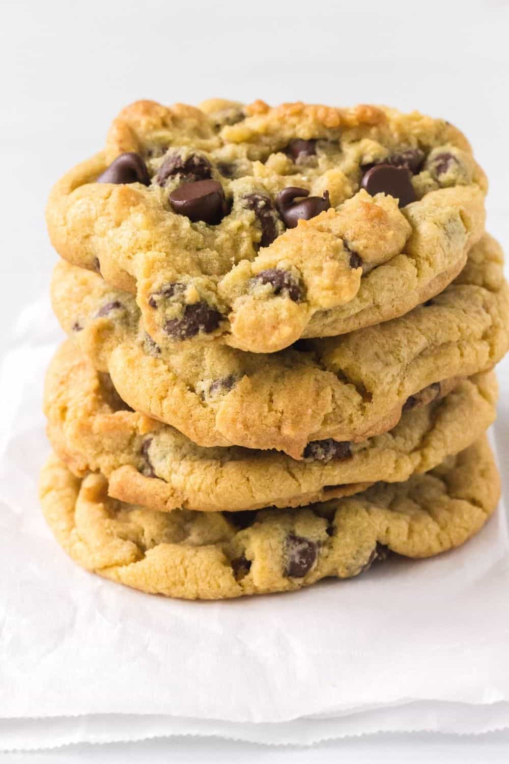 stack of homemade chocolate chip cookies, made from a recipe that doesn't require brown sugar, resting on a piece of parchment