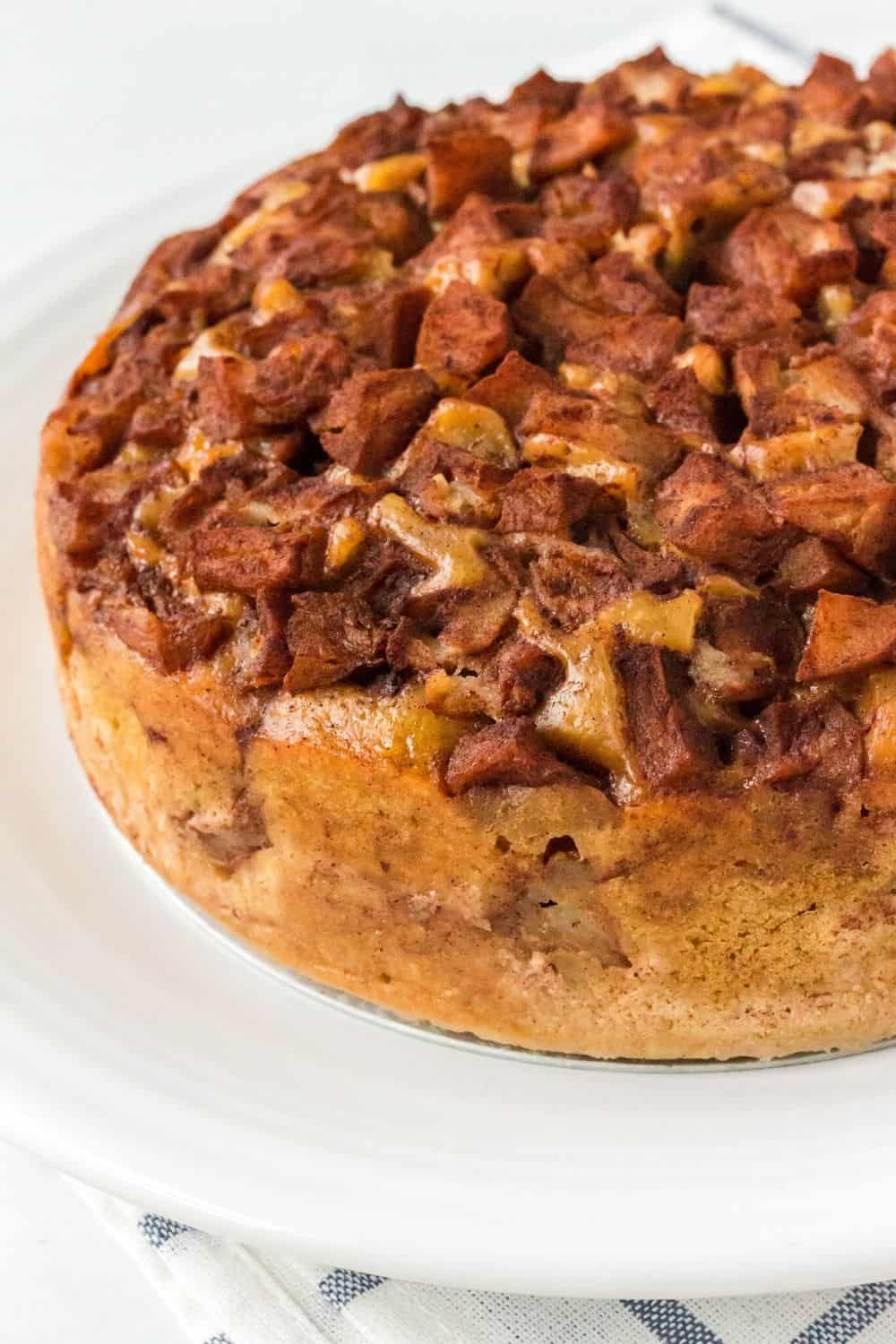 view of an unsliced pressure cooker apple cake served on a white plate