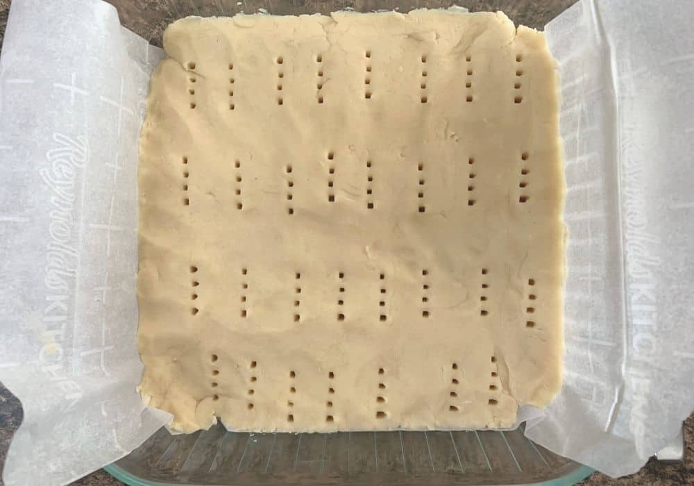 scottish shortbread dough pressed into a prepared pan and poked with the tines of a fork