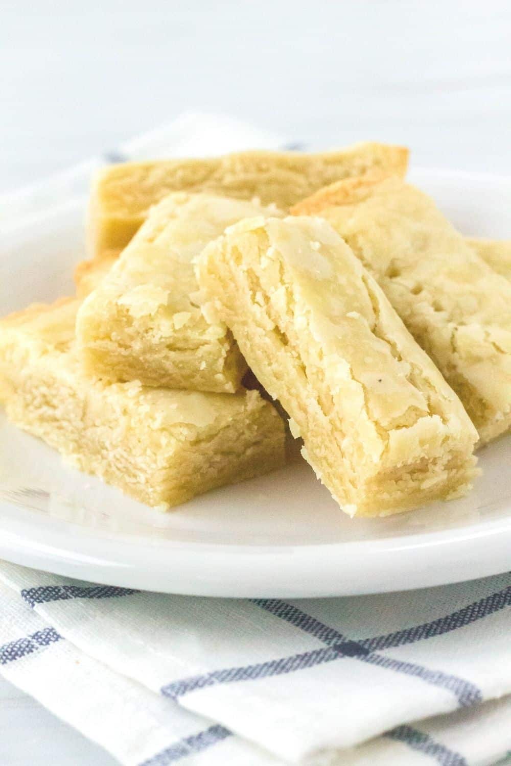 Scottish shortbread cookies served on a white plate atop a blue and white checkered napkin