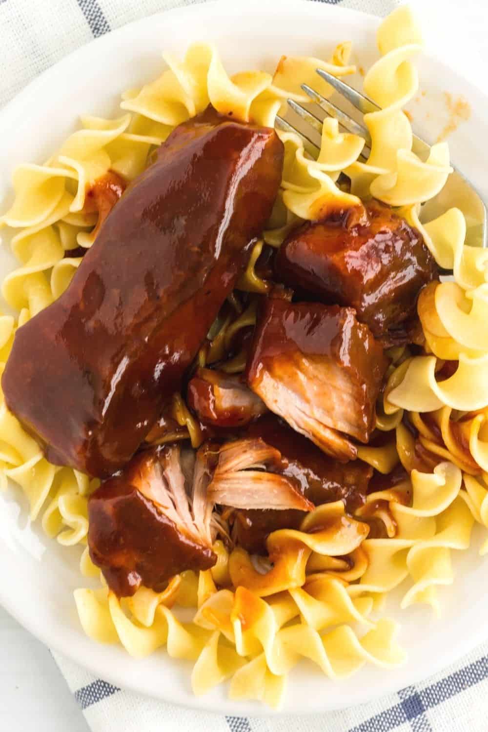 tender BBQ country style ribs served over noodles on a white plate
