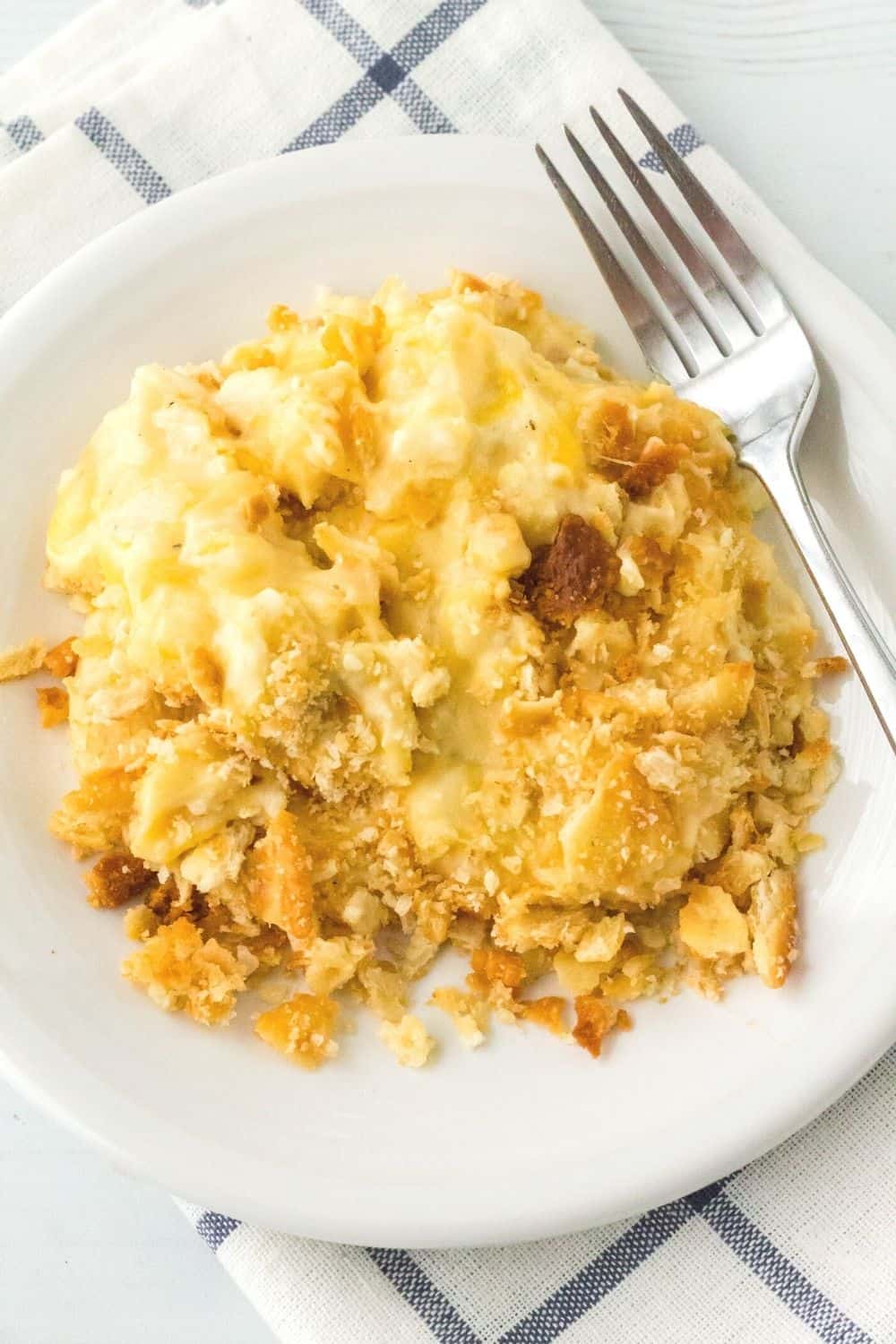 pressure cooker cheesy potatoes, topped with toasted cracker crumbs, served on a white plate with a fork