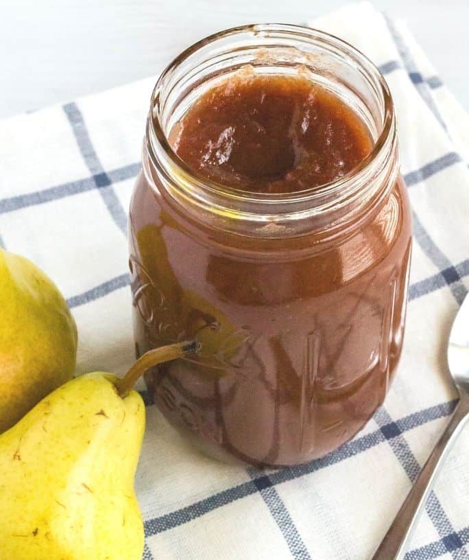 jar of pear butter on a blue and white npakin with two ripe pears next to it