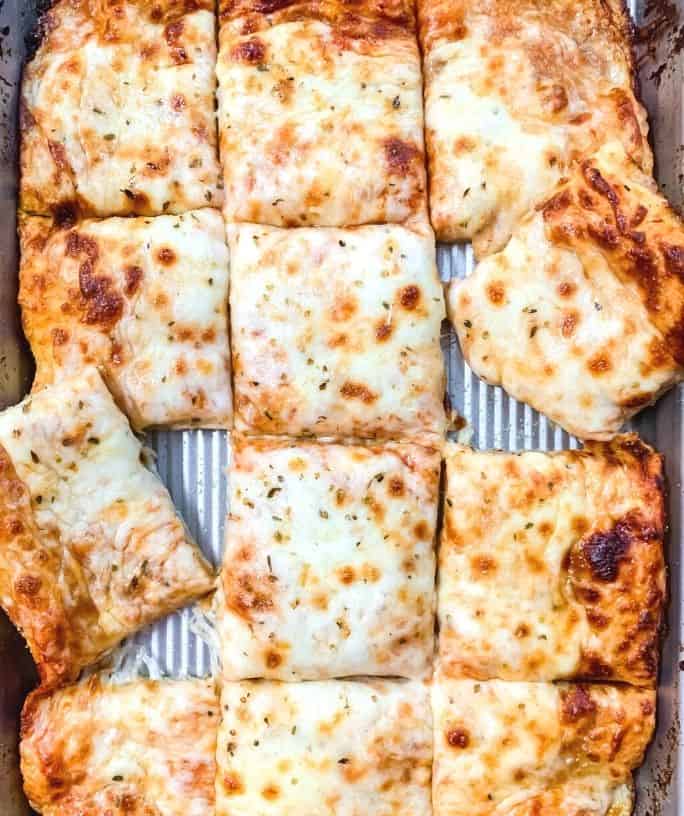 overhead view of rectangle slices of pizza on a baking sheet