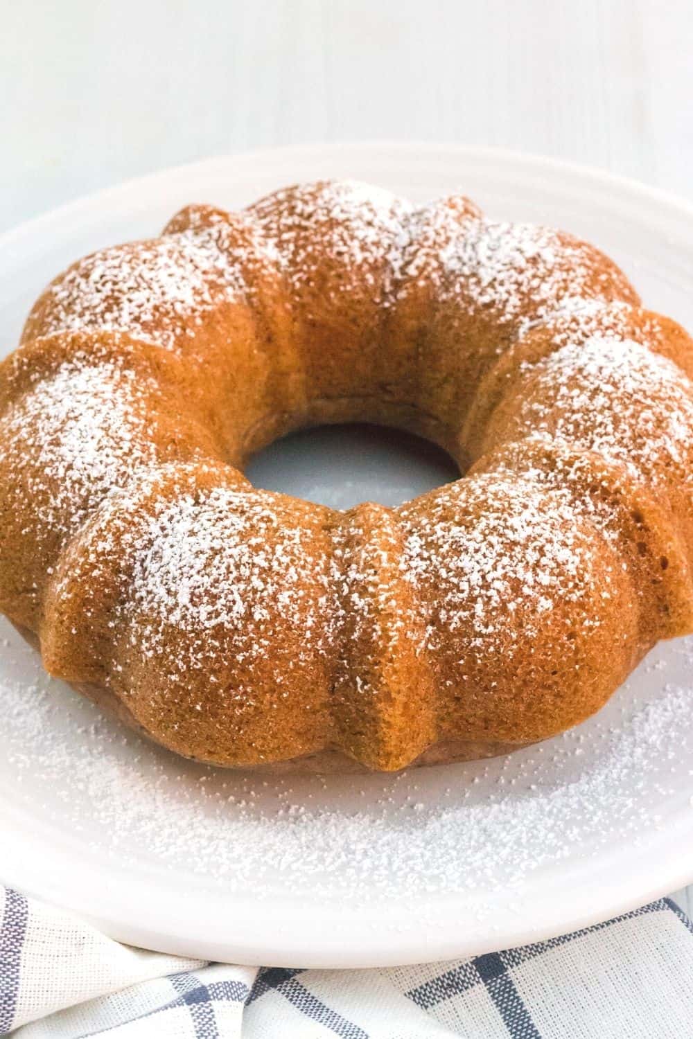 pressure cooker applesauce bundt cake sprinkled with powdered sugar and served on a white plate