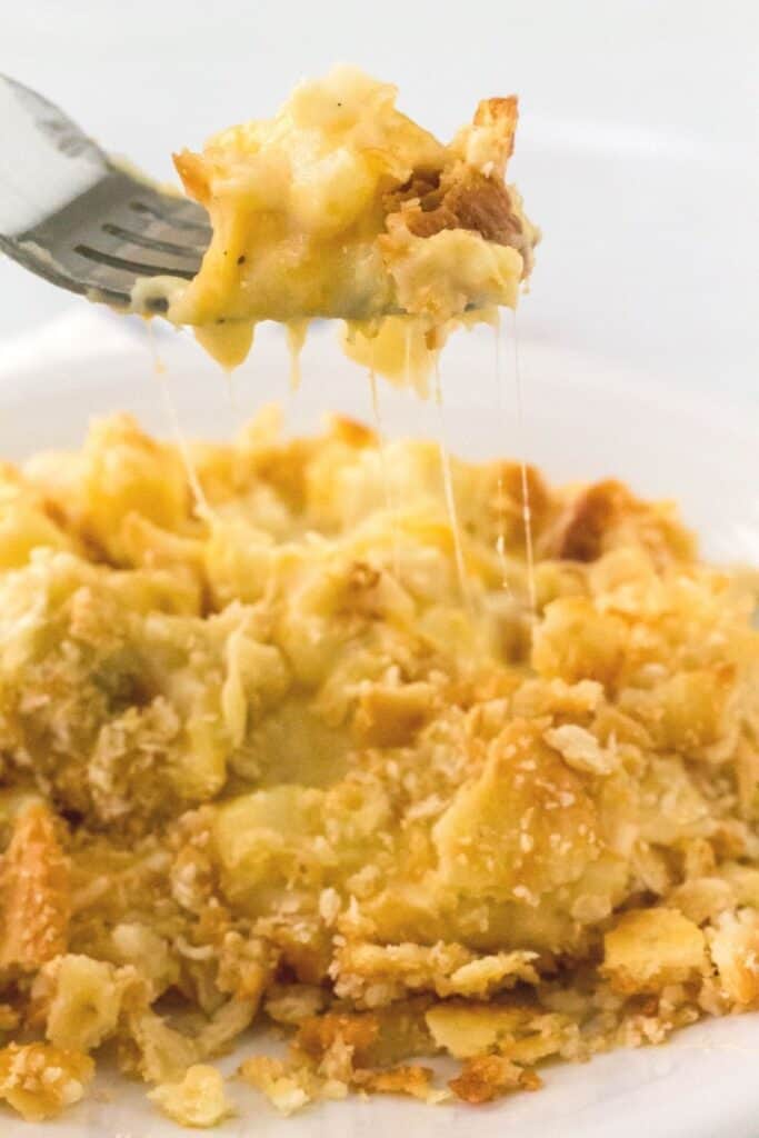 a fork lifts a bite of cheesy potatoes that were cooked in the Instant Pot
