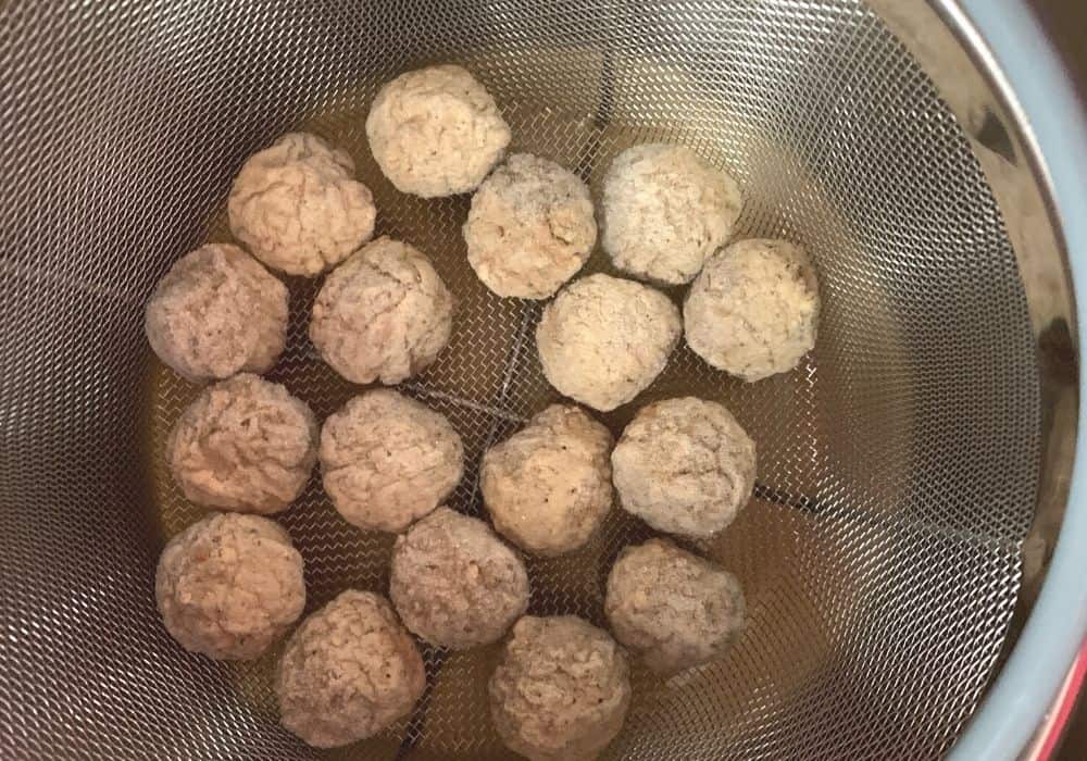 frozen meatballs in a steamer basket in the Instant Pot