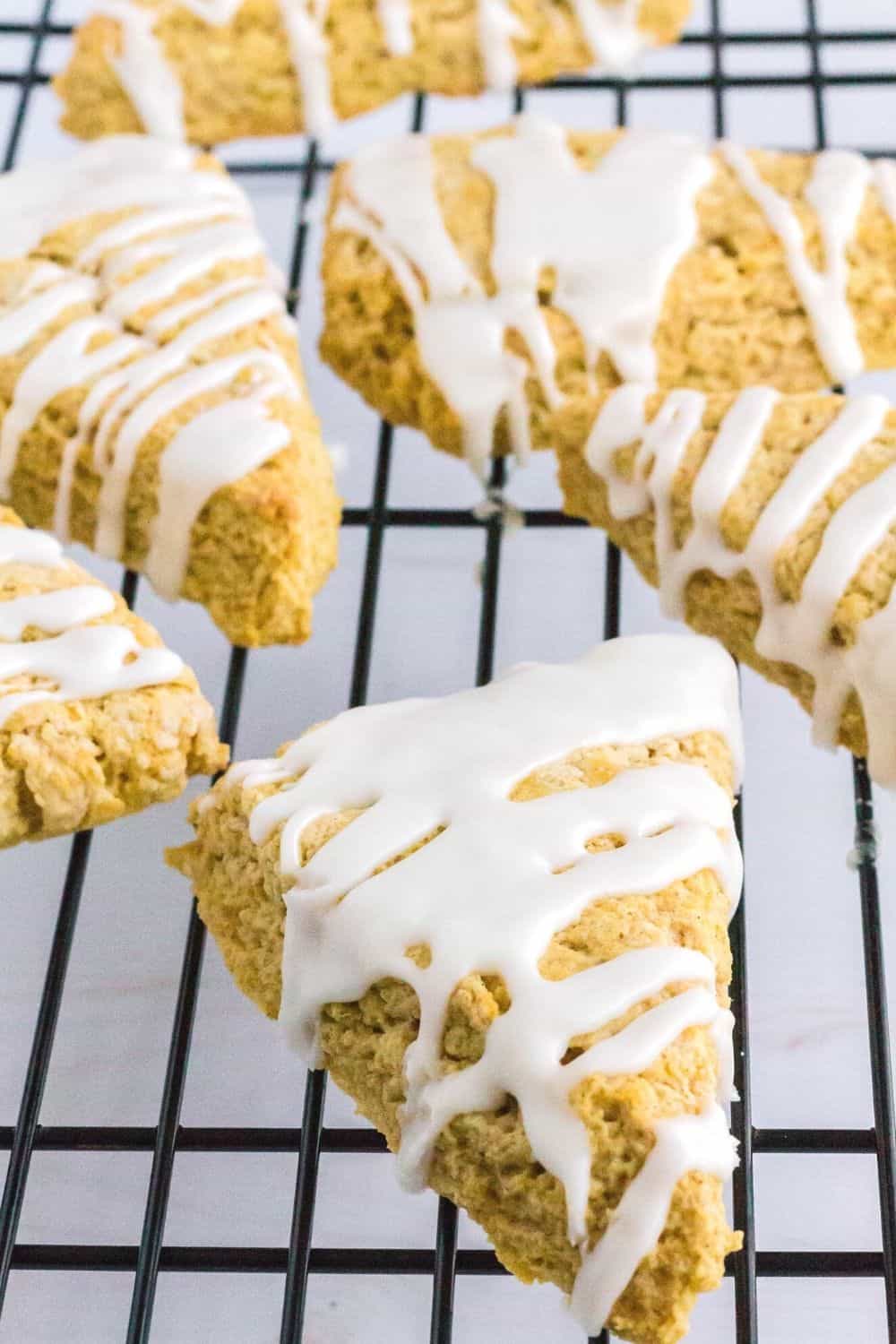 homemade pumpkin scones on a cooling rack, drizzled with vanilla icing