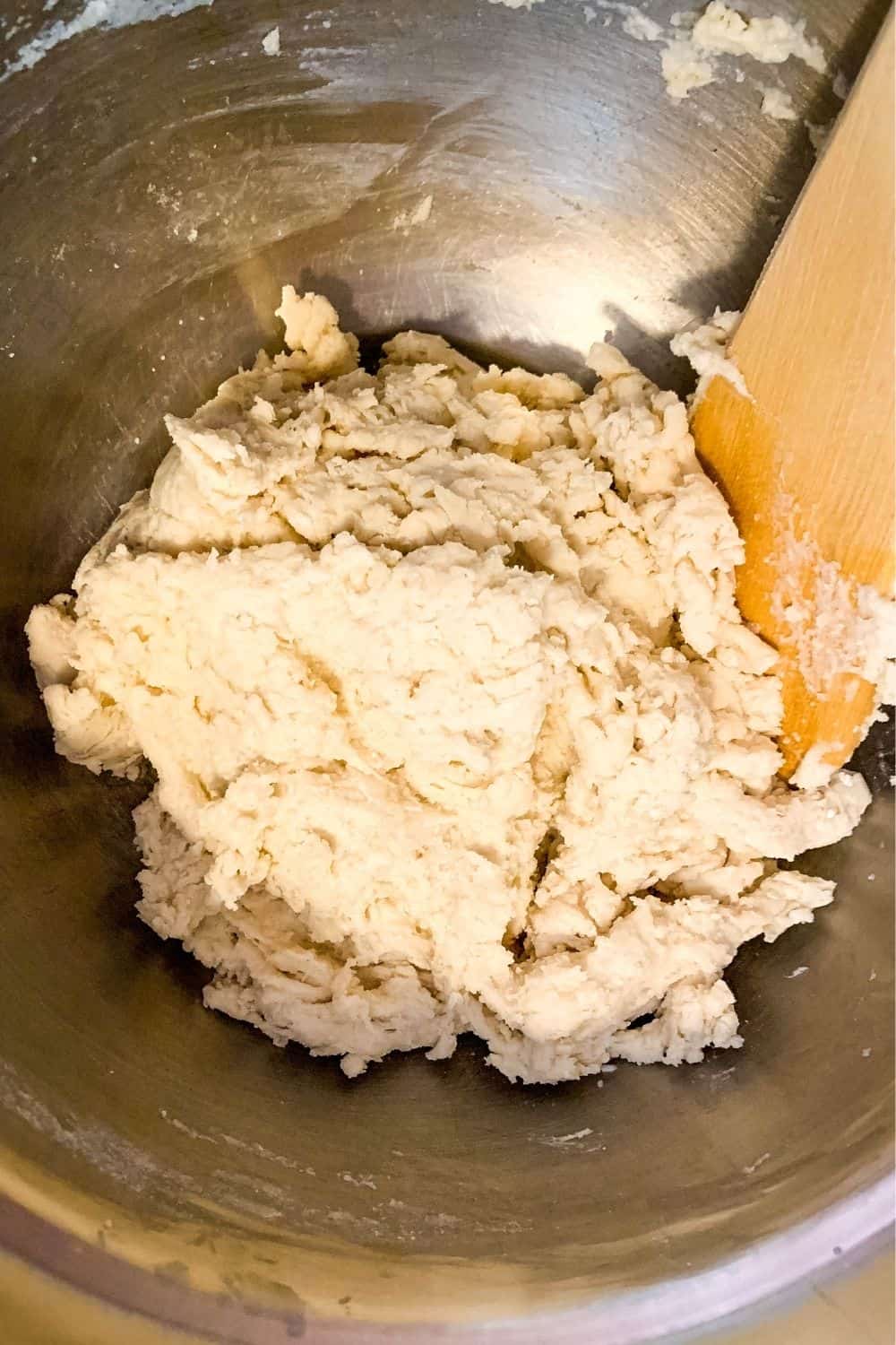 bisquick dumpling dough in a silver mixing bowl with a wooden spoon