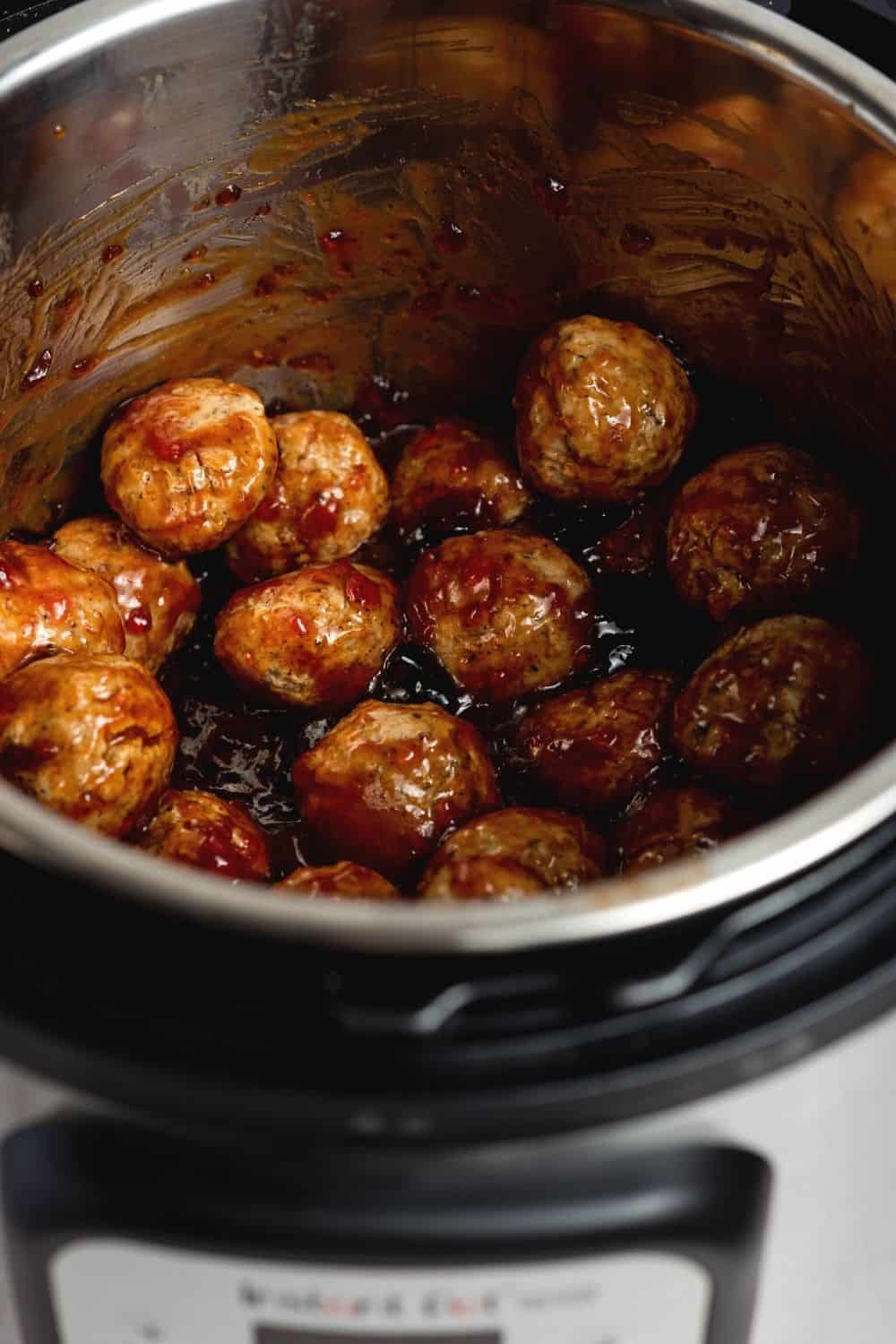 frozen meatballs stirred together with grape jelly and BBQ sauce for making party meatballs in the Instant Pot