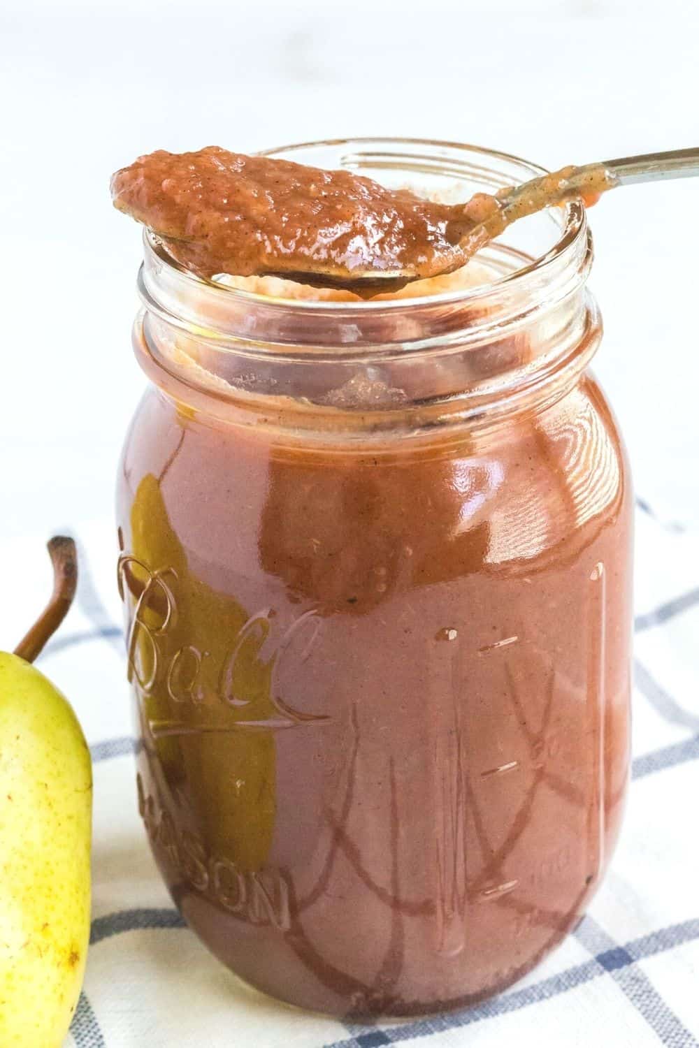 Ball jar of pear butter with a spoon resting on top