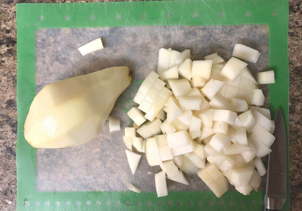 diced pears on a cutting board, with a peeled pear next to it