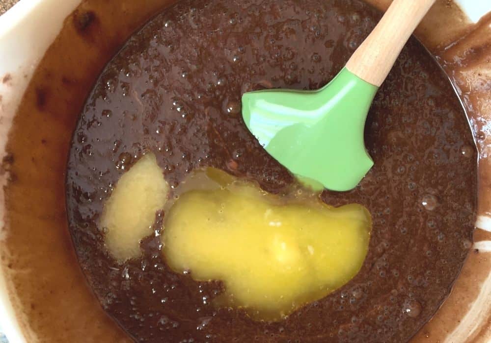 egg and melted butter added to chocolate cake batter in a mixing bowl