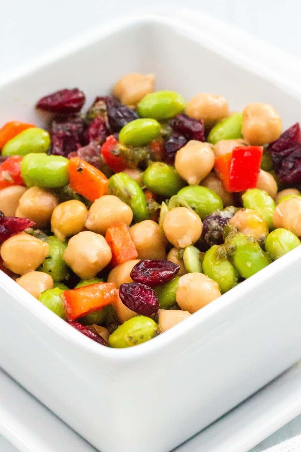 chickpea salad with cranberries, edamame, peppers, and carrots, served in a white bowl