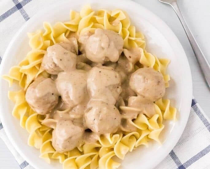 overhead view of a white plate with egg noodles topped with Instant Pot swedish meatballs