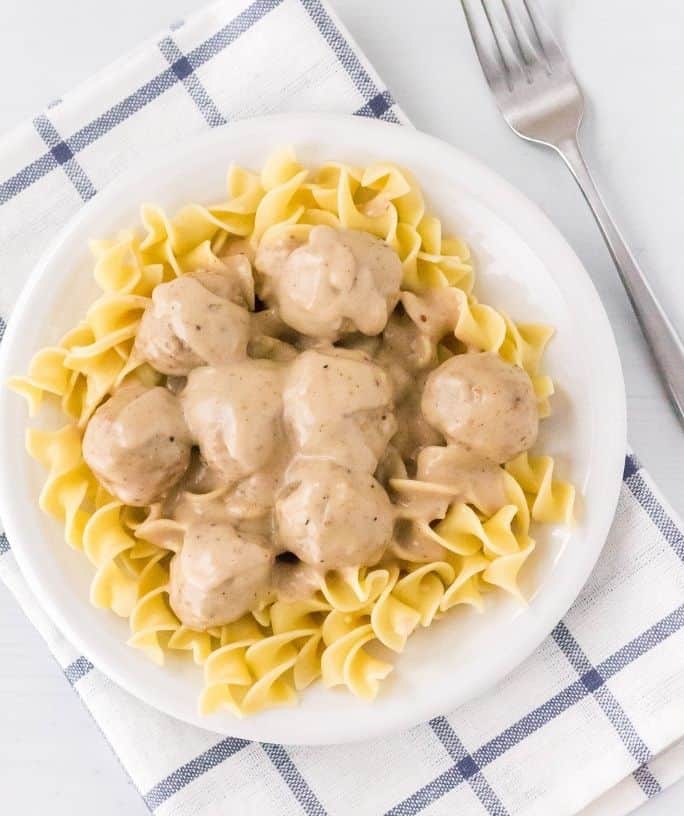 overhead view of a white plate with egg noodles topped with Instant Pot swedish meatballs
