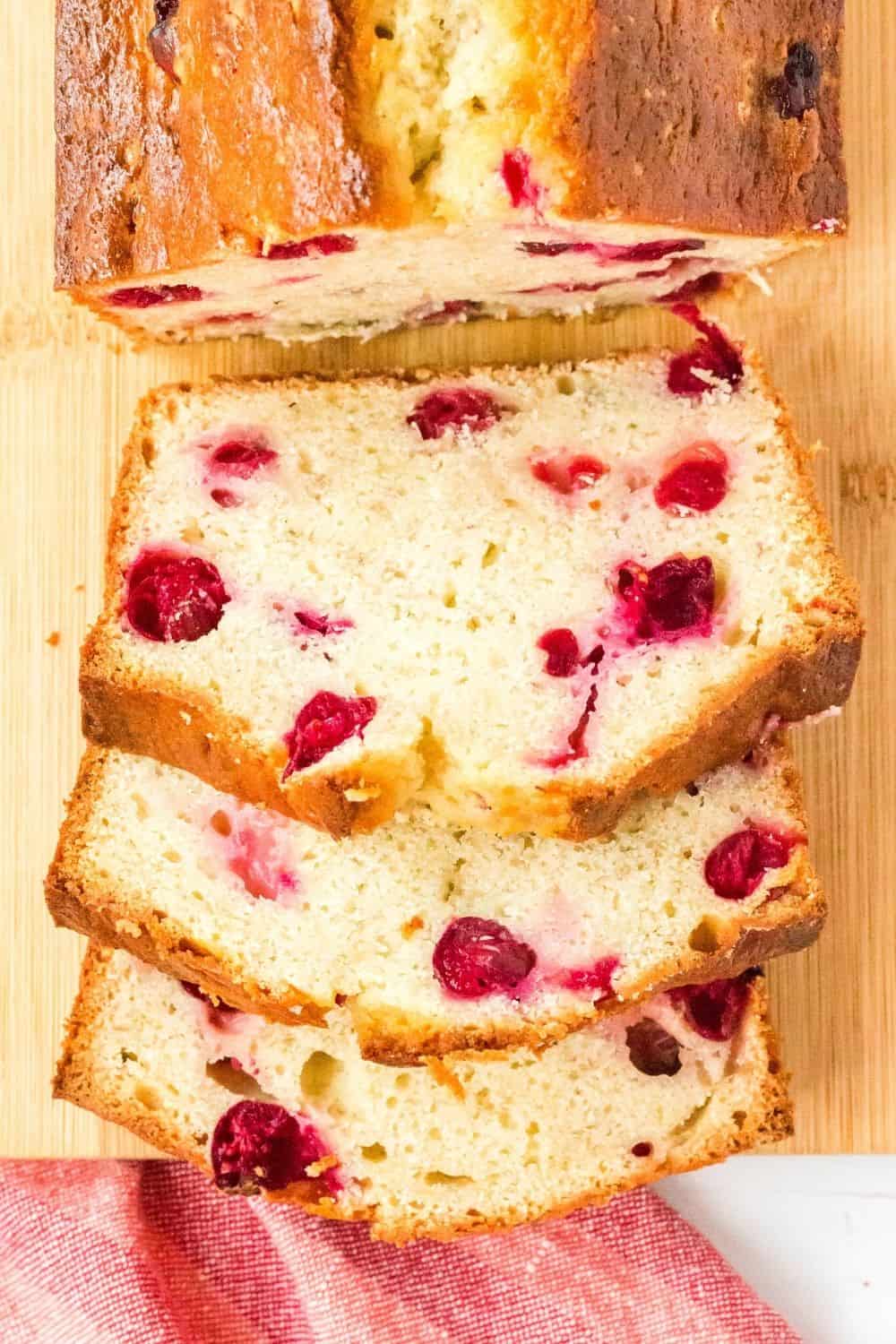 overhead view of a sliced loaf of banana cranberry bread on a cutting board