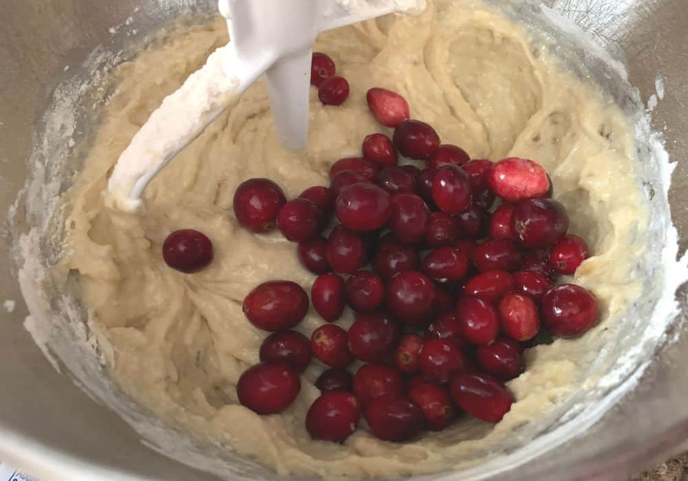fresh cranberries added to banana bread batter in a mixing bowl