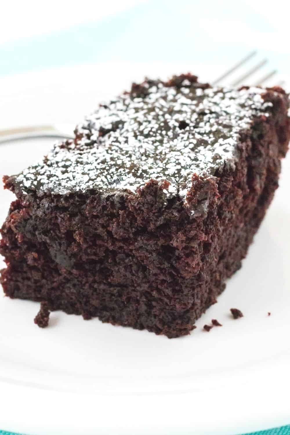 slice of decadent chocolate snack cake dusted with powdered sugar and served on a white plate