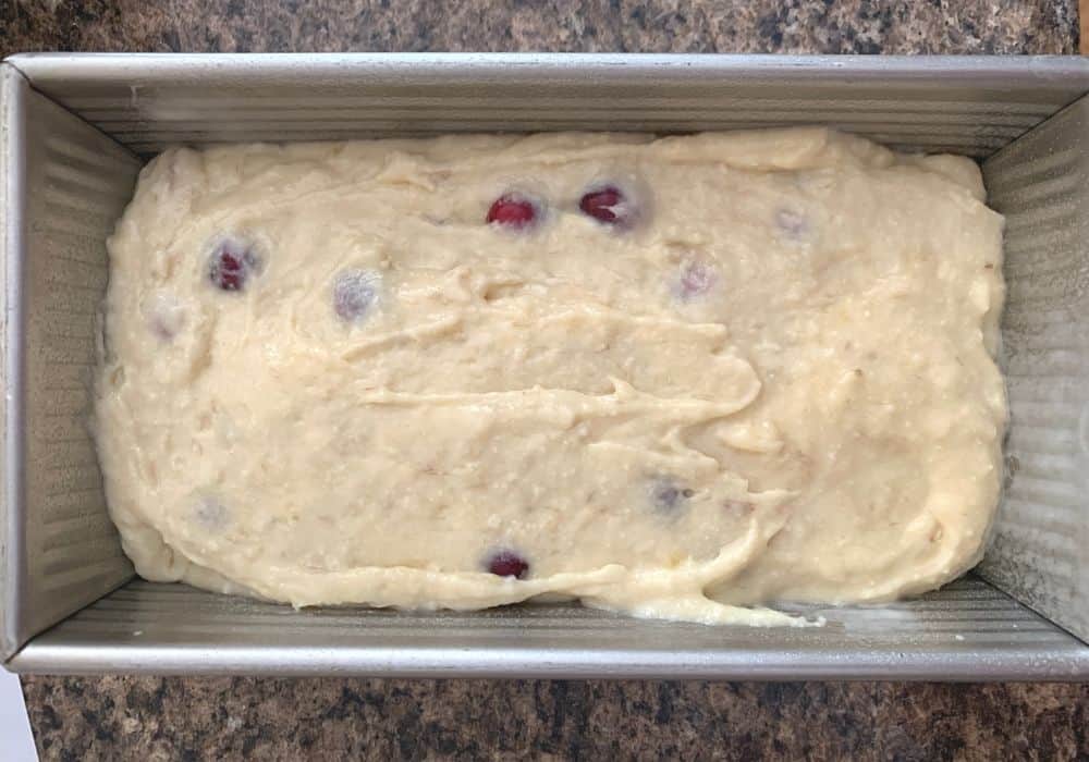 loaf pan with cranberry banana bread batter in it, ready to be baked