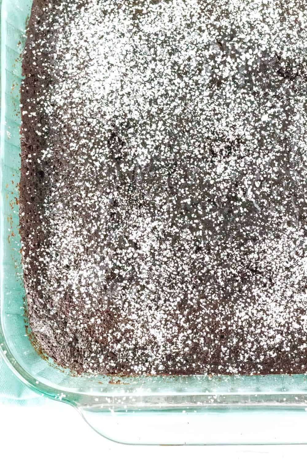 overhead view of a chocolate cake baked in a square pan and dusted with powdered sugar