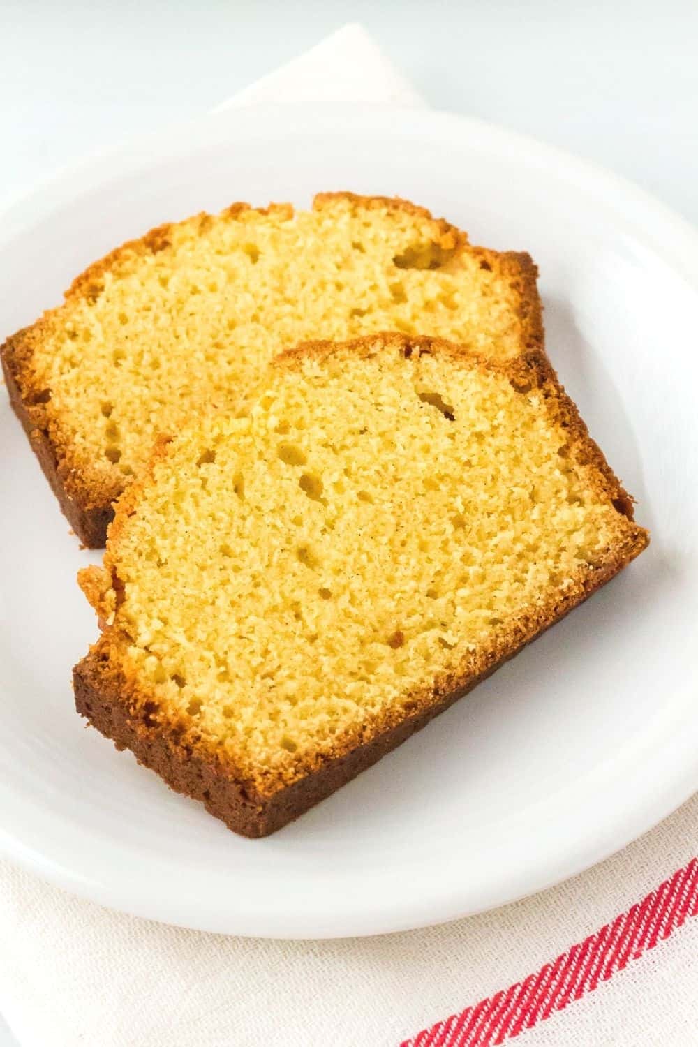 two slices of eggnog bread on a white plate, atop a red and white napkin