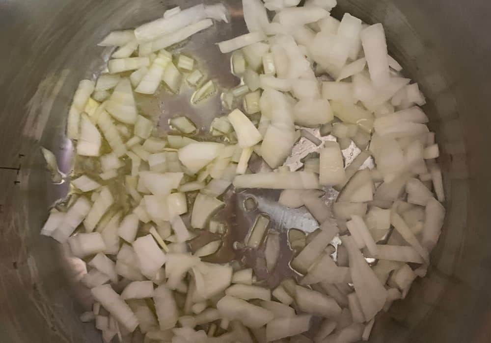 diced onions being sauteed in olive oil inn the instant pot