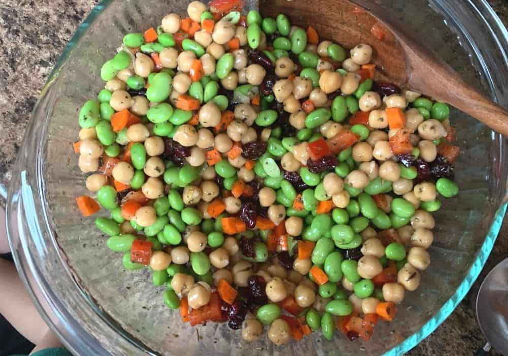 all ingredients mixed together in a glass bowl, making an aldi copycat chickpea and edamame salad