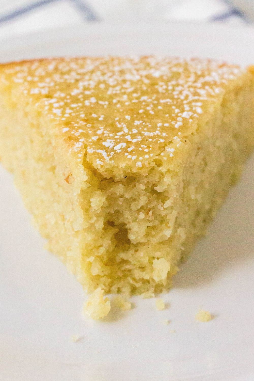 close-up view of a slice of homemade pear cake, made with whole unpeeled pears, served on a white plate. A bite has been taken out of the cake, showing the tender crumb.