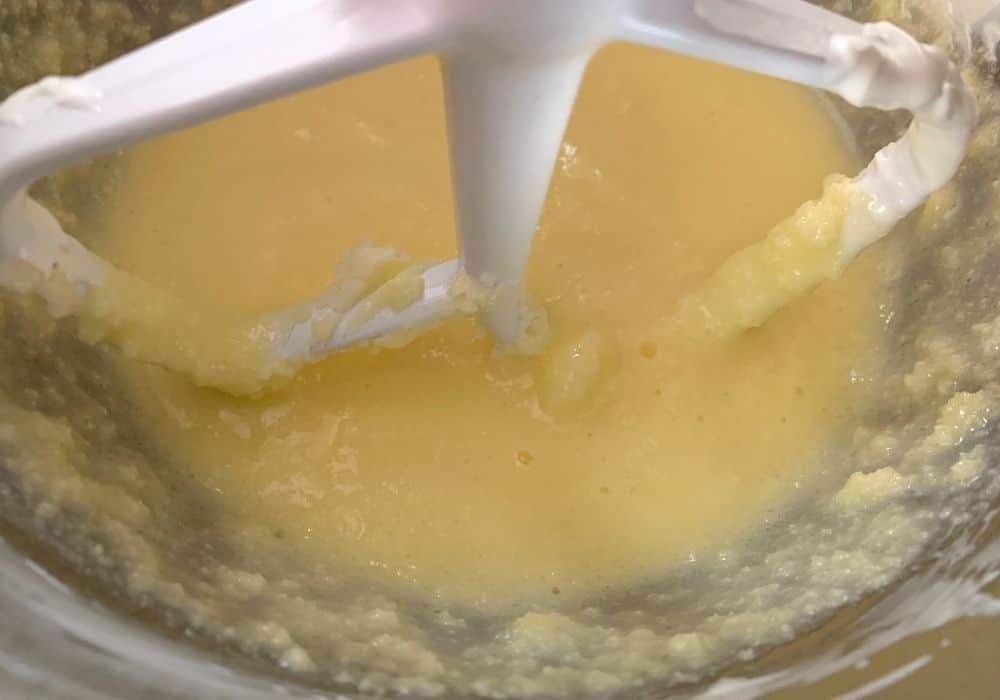 butter, sugar, eggs, and sour cream mixed together in the bowl of a stand mixer