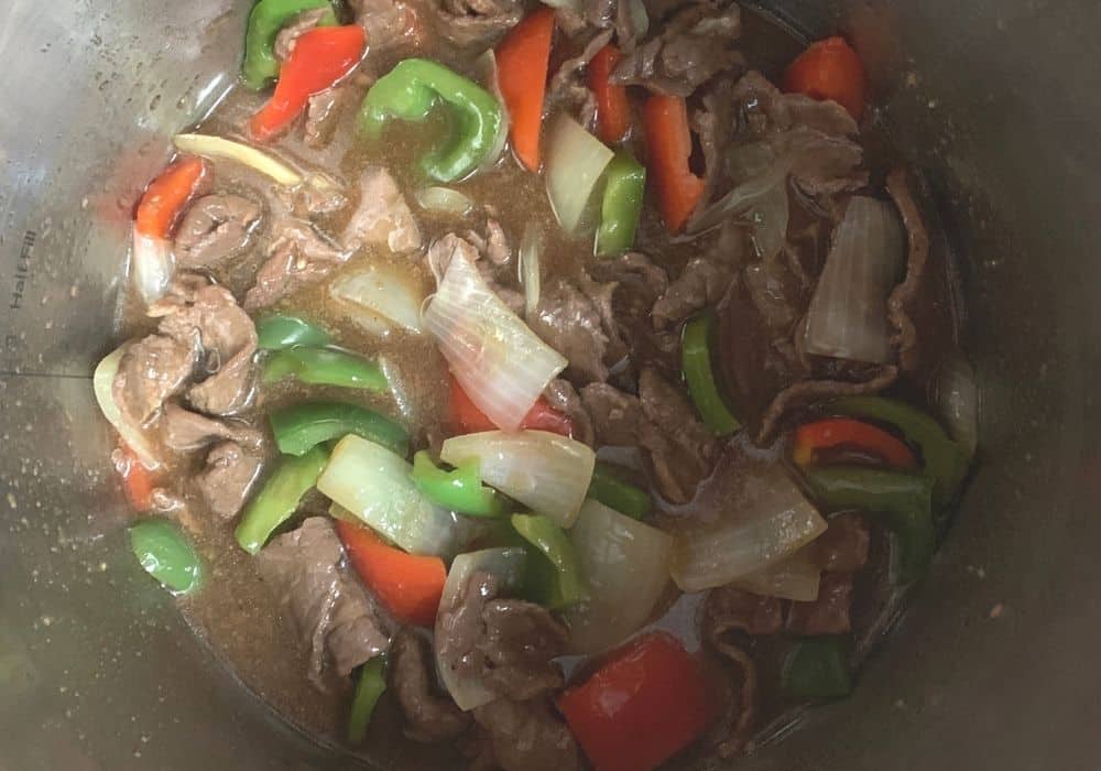 pressure cooker steak with peppers and onions, freshly cooked, in the insert pot of the Instant Pot