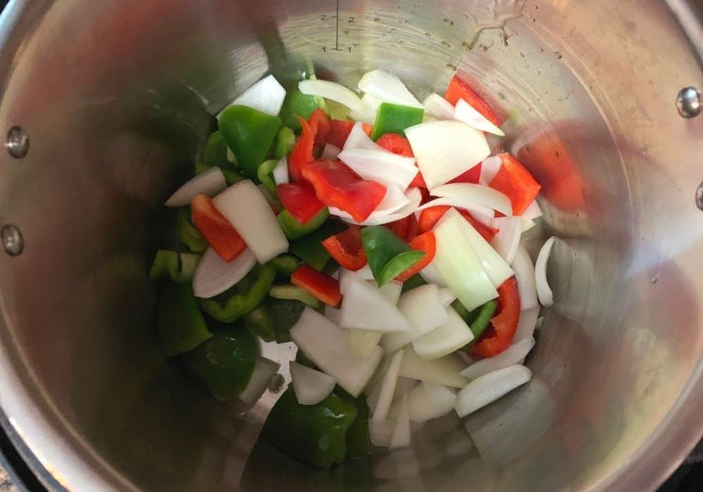chopped red and green bell peppers and onions in the insert pot of the Instant Pot