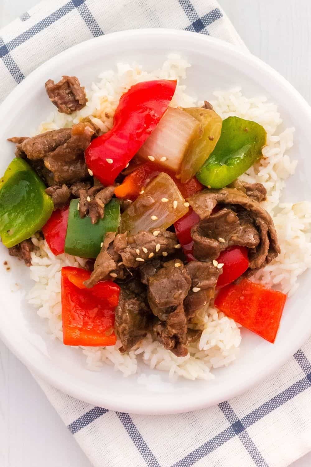 A white plate with a serving of white rice, plus Instant Pot Chinese pepper steak.