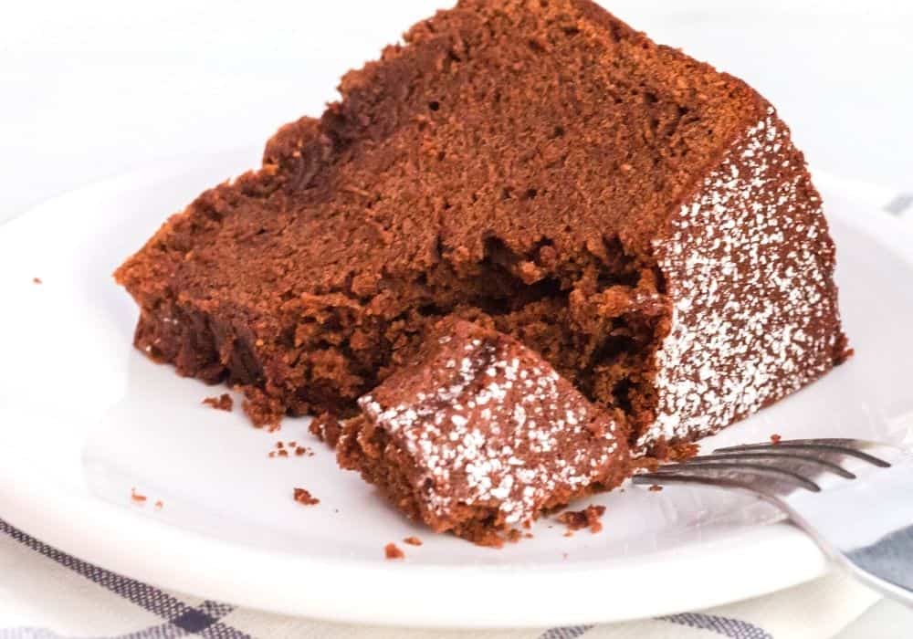 a slice of chocolate pound cake on its side, with a bite cut out by a fork