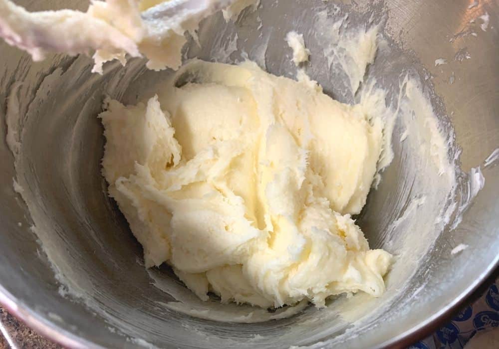 butter, cream cheese, and sugar mixed together in the bowl of a stand mixer