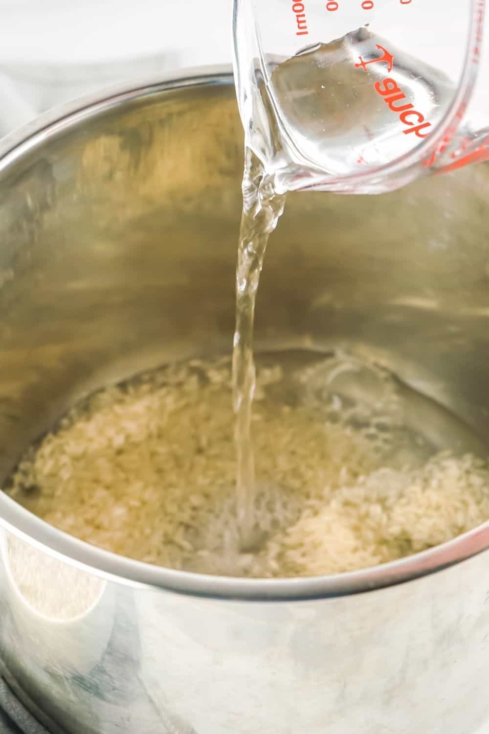 water being poured into the insert pot of the Instant Pot, where white rice has been added
