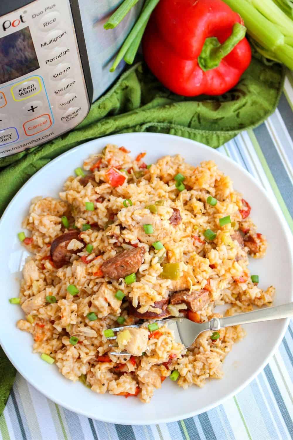 a helping of cajun jambalaya on a white plate in front of an Instant Pot pressure cooker