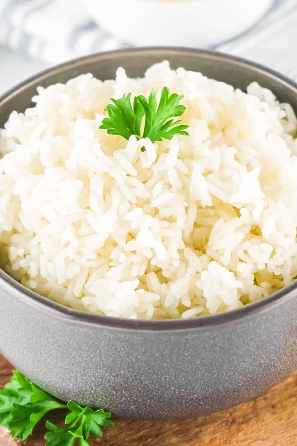 fluffy pressure cooker white rice in a brown bowl, garnished with parsley