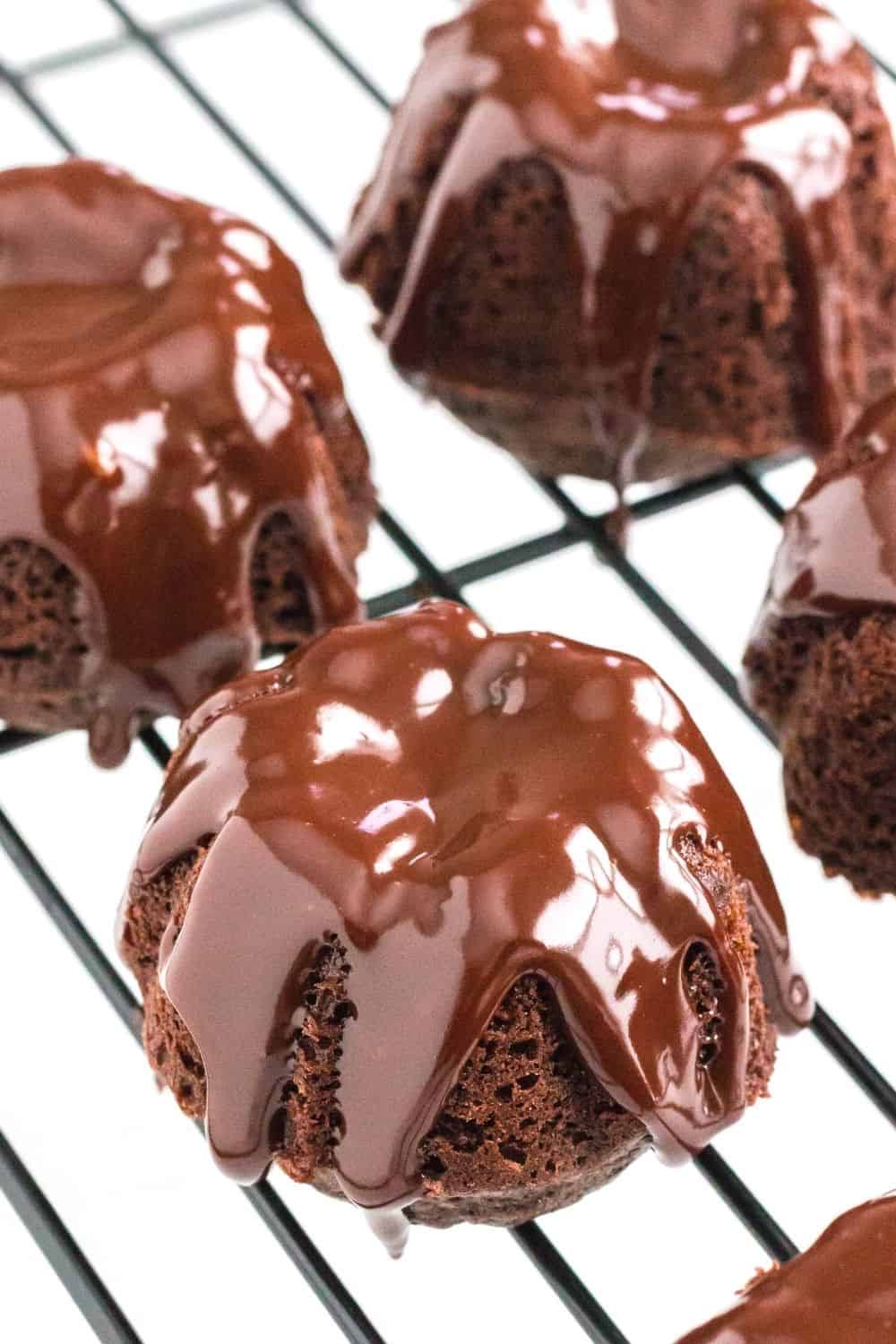 mini chocolate bundt cakes on a cooling rack, topped with satiny ganache