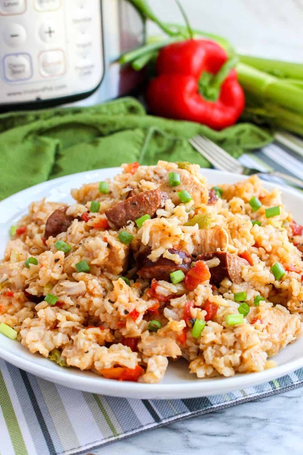 close-up view of jambalaya that was cooked in the instant pot served on a white plate, with a bell pepper and pressure cooker in the background