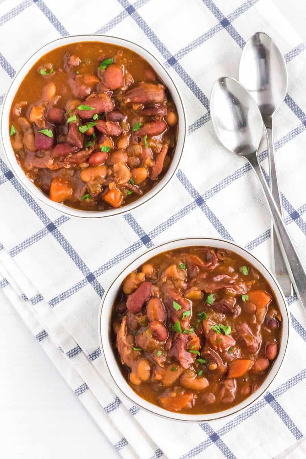 two bowls of Instant Pot HamBeen soup on a blue and white napkin, with two spoons next to them