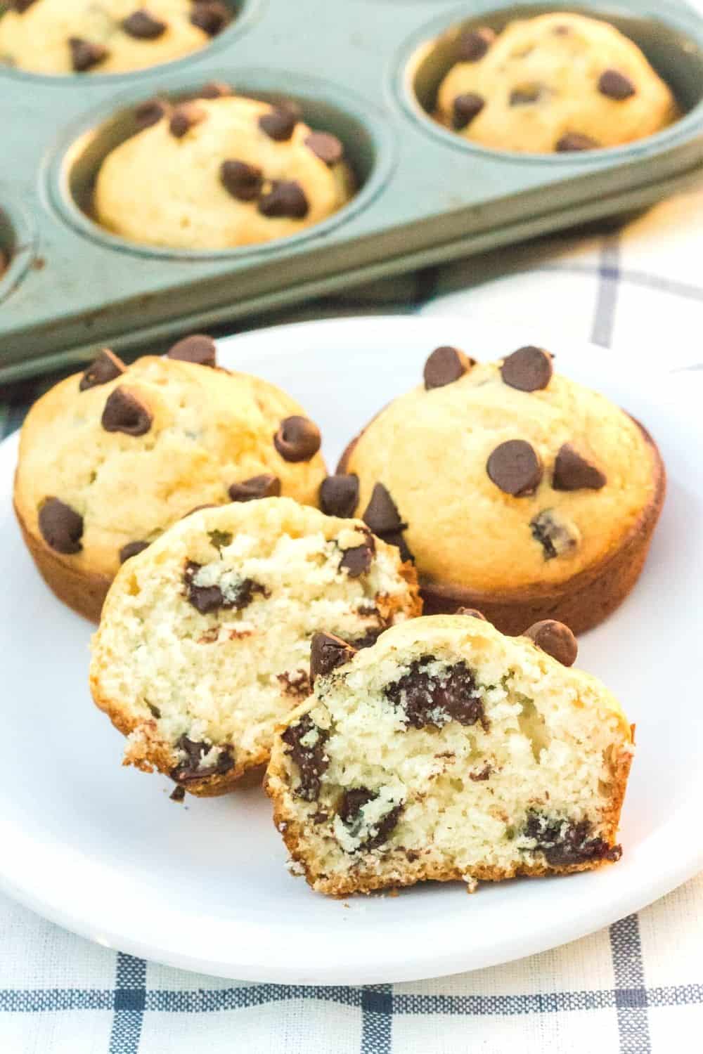 three chocolate chip muffins made with bisquick on a white plate, with one muffin cut in half