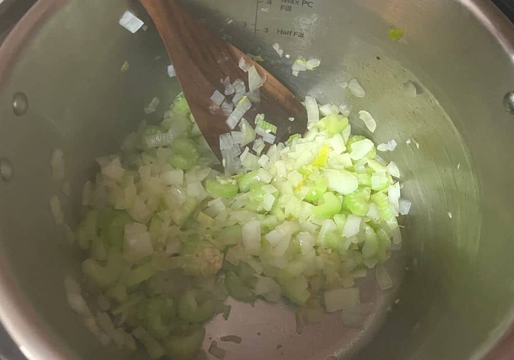 onions and celery being sauteed in the insert pot of the Instant Pot