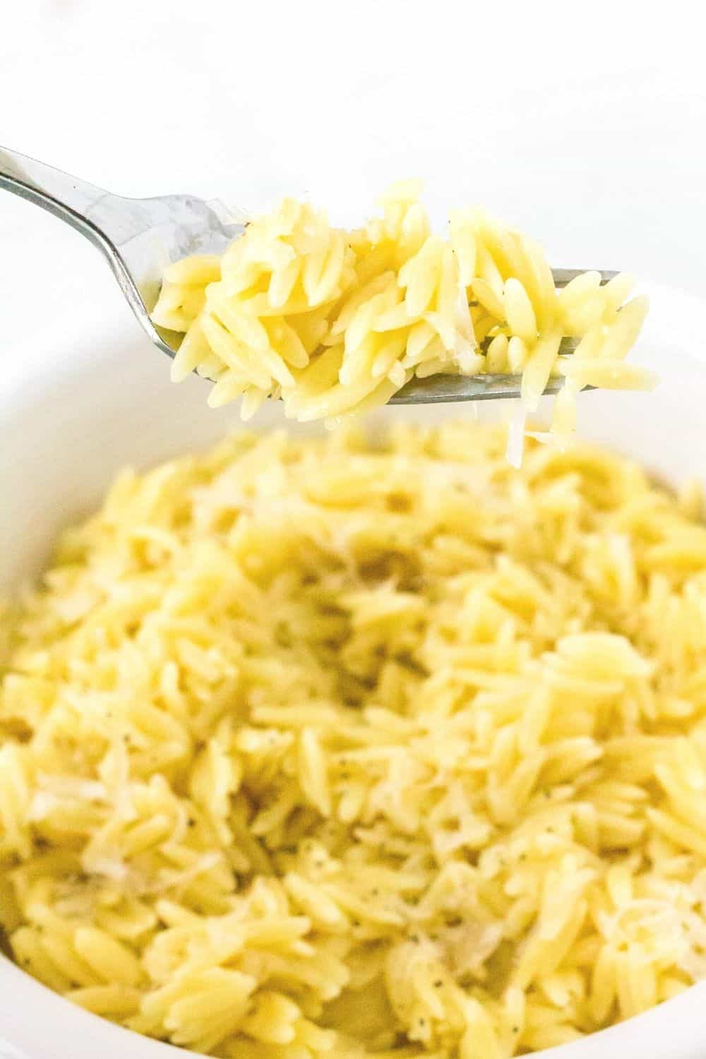 a fork lifts a bite of orzo cooked in the instant pot