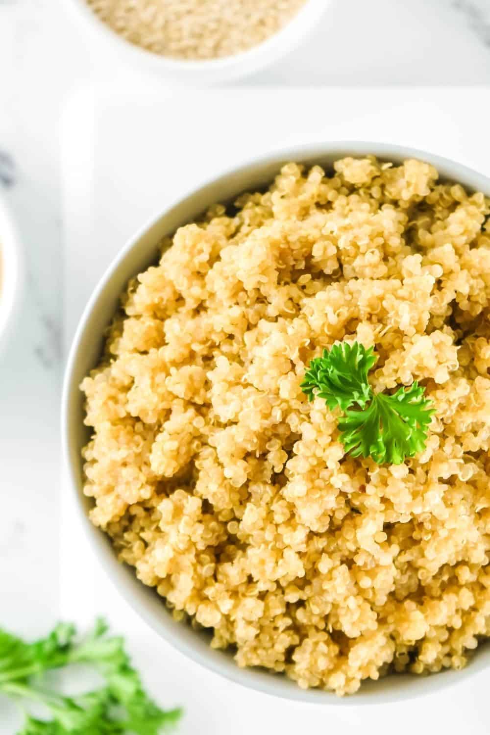 overhead view of a white bowl of pressure cooker quinoa, garnished with parsley